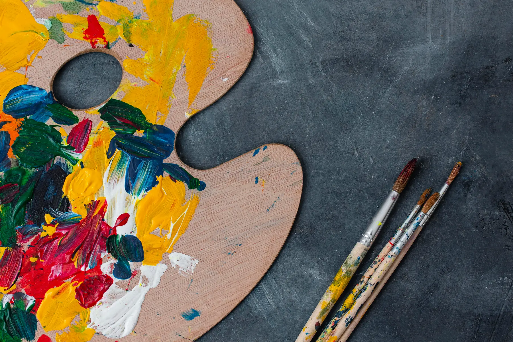 An artist's palette, brushes and paints on a table